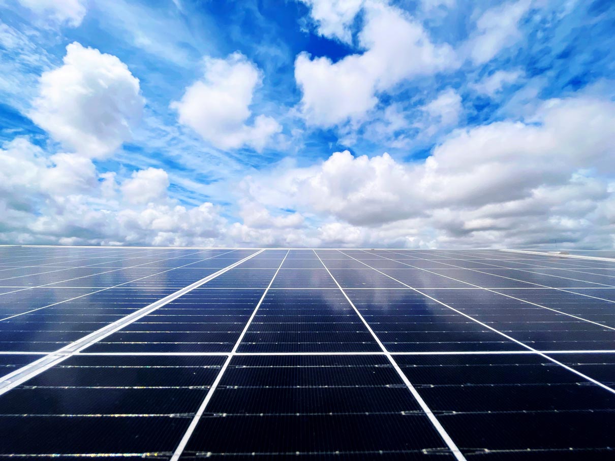 fotografia de um céu azul com nuvens reflectido num conjunto de paineis solares